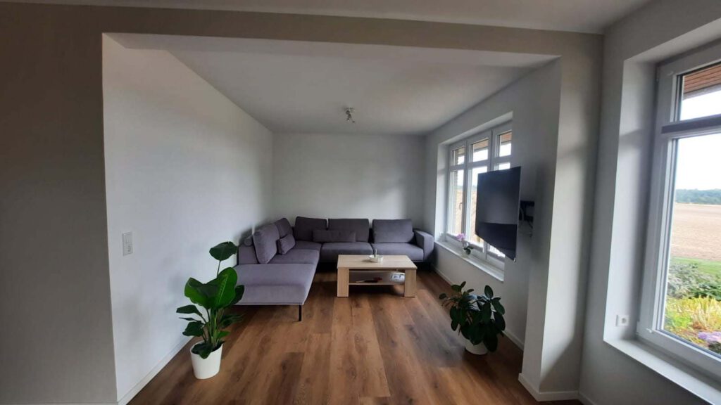 Auf dem Bild ist ein Wohnzimmer zu sehen, welches gerade saniert worden ist. In einen Modernen style. Jedoch in einem Winkel, in dem man perfekt die Sofaecke erkennen kann.