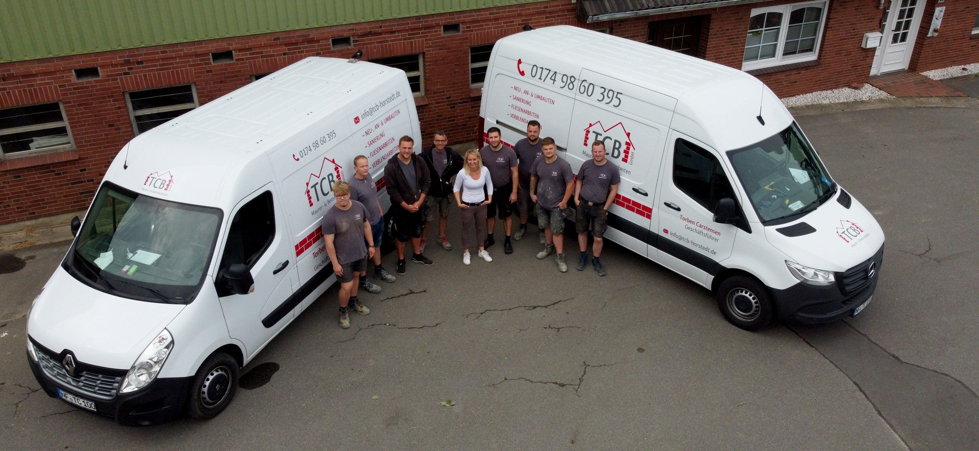 Das TCB GmbH Team mit zwei beschrifteten Firmenfahrzeugen auf einem Betriebsgelände